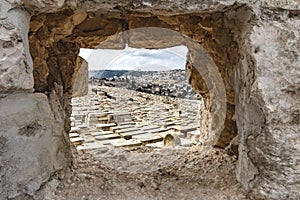 Israel Jerusalem, mount zion, a unique view through a rock to the old city, with many tombs in the foreground,