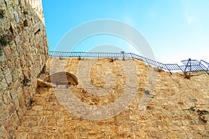 Israel Jerusalem, view of the old city wall, photographed from below with the background of the fence on the wall, against a brigh