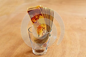 Israel money, Shekel. Israeli money bills banknotes of 100 shekel in transparent glass mug