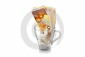 Israeli money bills banknotes of 100 shekel in transparent glass mug on a white isolated background
