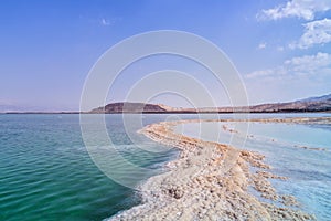 Israel. The salt flats of the Dead Sea. Blue sky and mountains in the background. The path from salt picturesquely curls in salty