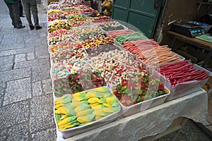 Israel street stall selling colorful confectionery, sweets, candy pencils, fruit-jellies in plastic boxes. Walking along row of