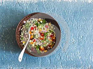 Israeli cous cous ptitim vegetables tabbouleh salad on a blue background, top view. Vegetarian food