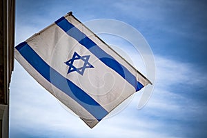 Israeli flag against blue sky and white clouds