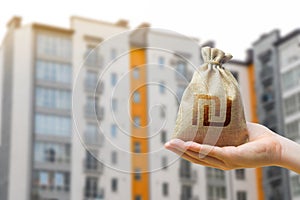 Israeli shekel bag against the background of modern high-rise buildings. Investing in the purchase of real estate. Affordable