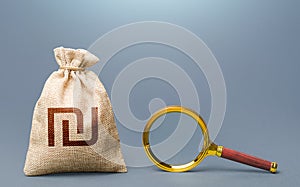 Israeli shekel money bag and magnifying glass. Financial audit. Origin of capital and legality of funds. Search for financing