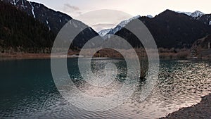 Issyk mountain lake with mirror water at sunset.