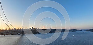 Istanbul Bosphorus Bridge and City Skyline in Background with Turkish Flag at Beautiful Sunset, Aerial slide orbiting