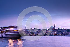 Istanbul cityscape - panoramic scenic view of mosque with ferry boat at sunset. Long exposure landscape of Istanbul at night