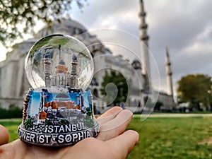 Istanbul snow globe on a palm against the background of the Suleymaniye Mosque in Istanbul Turkey. Travel to Turkey concept.