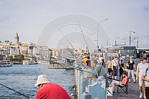 Istanbul, Turkey - August 13, 2022: Local citizens fishing at golden horn on Galata Bridge before sunset with Galata