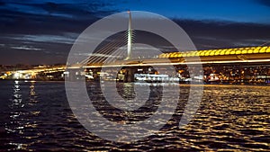 Istanbul, Turkey - February 2023: view on the calm sea water at Bosphorus at night and illuminated bridge to Golden Horn