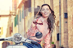 Itaian female sitting on scooter at old town's street.