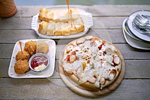 Italain pizza ,chicken ball and bread butter sungar on top read to eaton wood table photo