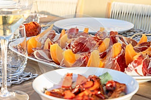 An Italian alfresco dining setting, featuring a plate of Prosciutto paired with sweet melon slices