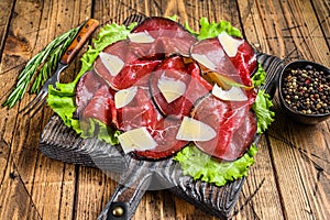 Italian Antipasti Bresaola meat cut with green salad and Parmesan. wooden background. Top view