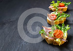 Italian antipasti crostini with ham, salad and tomato