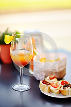 Italian aperitives/aperitif: glass of cocktail sparkling wine with Aperol and appetizer platter on the table