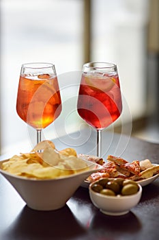 Italian aperitives/aperitif: glass of cocktail sparkling wine with Aperol and appetizer platter on the table