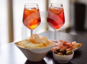 Italian aperitives/aperitif: glass of cocktail sparkling wine with Aperol and appetizer platter on the table