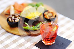 Italian aperitives aperitif: glass of cocktail (sparkling wine with Aperol) and appetizer platter on the table