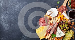 Italian appetizers or antipasto set with gourmet food on black stone table top view. Mixed delicatessen of cheese and meat snacks. photo