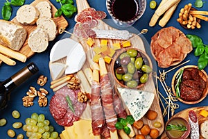 Italian appetizers or antipasto set with gourmet food on kitchen table top view. Mixed delicatessen of cheese and meat snacks