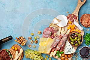 Italian appetizers or antipasto set with gourmet food on table top view. Mixed delicatessen of cheese and meat snacks with wine