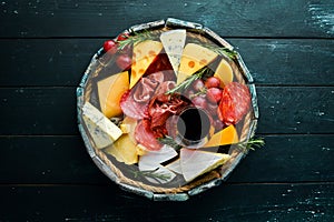 Italian appetizers. Cheese, wine, salami and prosciutto on a black stone background. Top view.