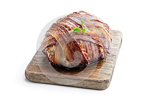Italian bacon wrapped meatloaf on wooden board isolated on white