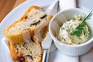 Italian bread with dried tomato and olive, chive butter with dill in bowl