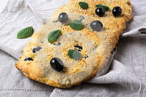 Italian bread focaccia with olive, garlic and herbs on the linen