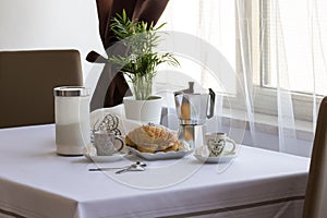 Italian breakfast: coffee, croissants, pasticiotto leccese, moka on the table, white background in the kitchen