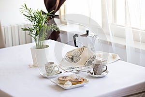 Italian breakfast for two person: coffee, croissants, pasticiotto leccese on the table, white background in the kitchen