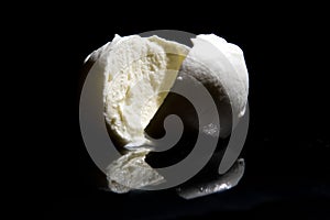 Italian buffalo mozzarella cheese from Campania region Italy on a black mirrored background with cutting light