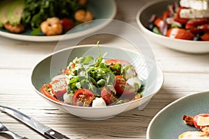 Italian caprese salad in restaurant. Fresh mozzarella, cherry tomatoes and basil leaf with pesto sauce. Organic and