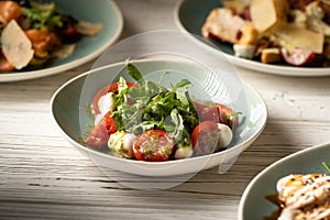 Italian caprese salad with tomatoes, mozzarella cheese, basil and olive oil serving on plate on table