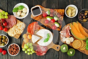 Italian charcuterie table scene against a dark wood background. Top view.