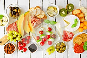 Italian charcuterie table scene against a white wood background. Overhead view.