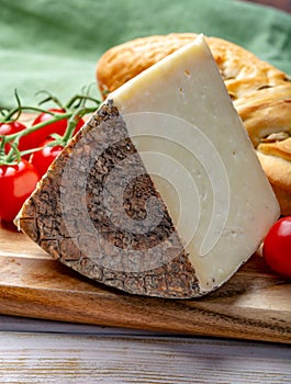 Italian cheese, piece of mature Tuscan Pecorino sheep cheese served with olive bread and tomatoes