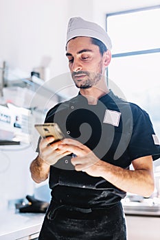 Italian chef with mobile phone in restaurant kitchen