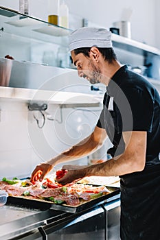 Italian chef pizzaiolo making sicilian pizza in restaurant kitchen