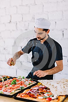 Italian chef pizzaiolo making sicilian pizza in restaurant kitchen