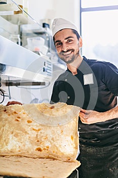 Italian chef pizzaiolo with pizza dough in restaurant kitchen