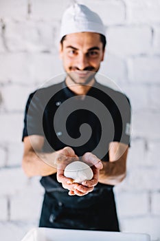 Italian chef pizzaiolo with pizza dough in restaurant kitchen