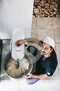 Italian chef pizzaiolo preparing dough for pizza in mixer