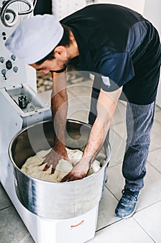 Italian chef pizzaiolo preparing dough for pizza in mixer
