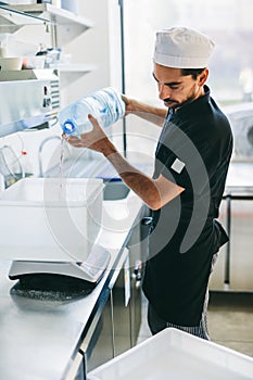 Italian chef pizzaiolo preparing pizza dough in restaurant kitchen