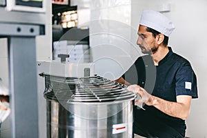 Italian chef pizzaiolo preparing pizza dough in restaurant kitchen