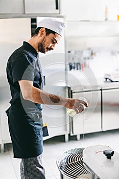 Italian chef pizzaiolo preparing pizza dough in restaurant kitchen